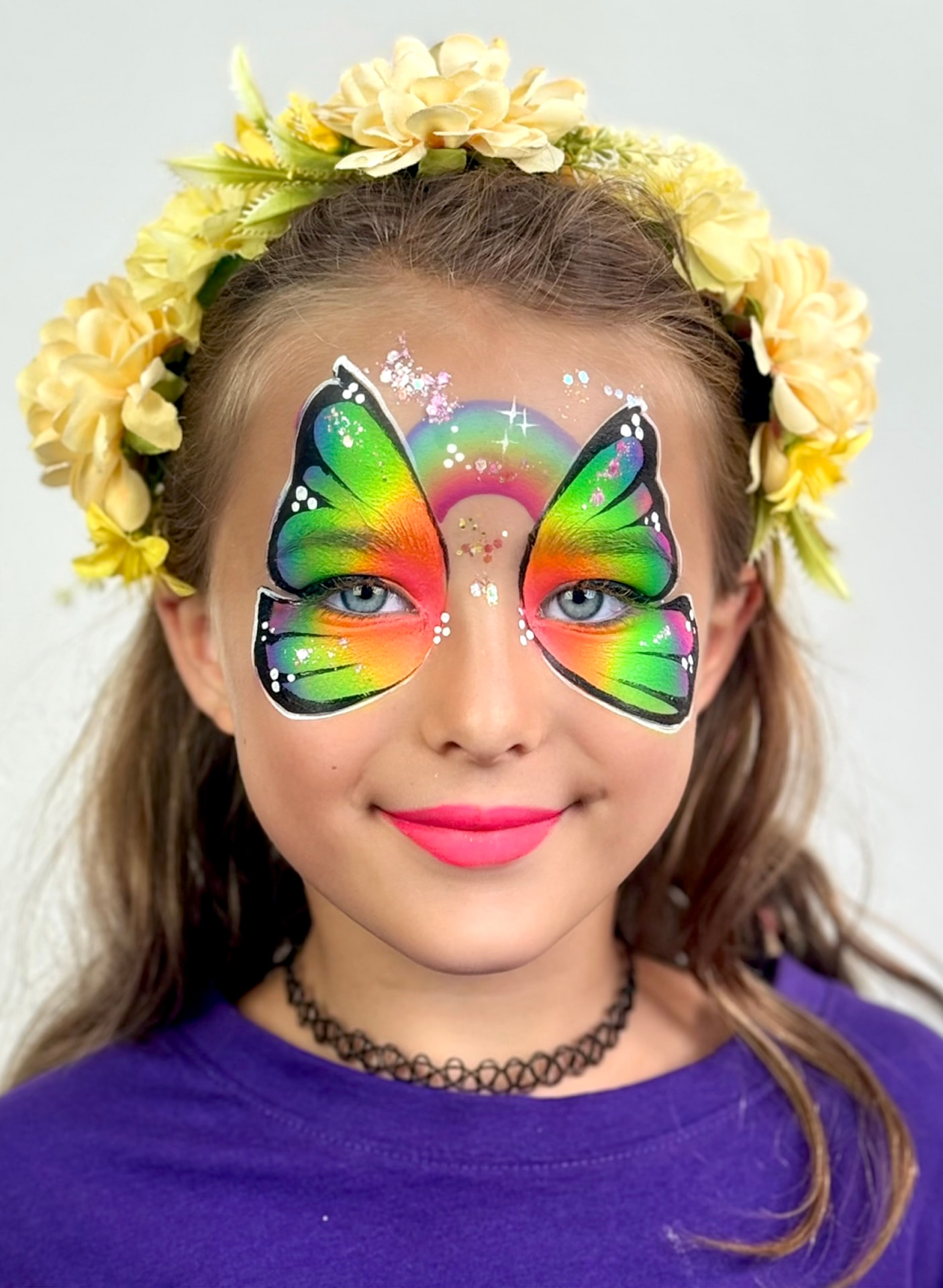 Bambina con una farfalla arcobaleno dipinta sul viso